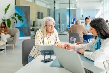 Woman talks with banker at a desk.